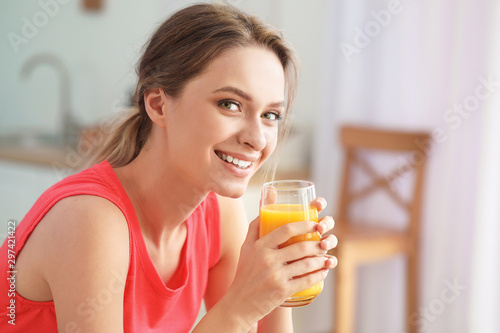 Young woman drinking healthy juice in kitchen. Diet concept
