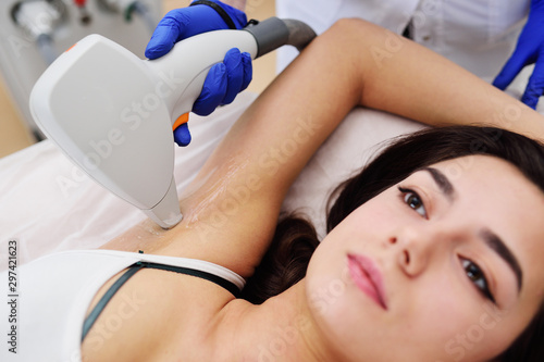 a young woman in a modern cosmetology clinic on the procedure of laser hair removal of the armpit area