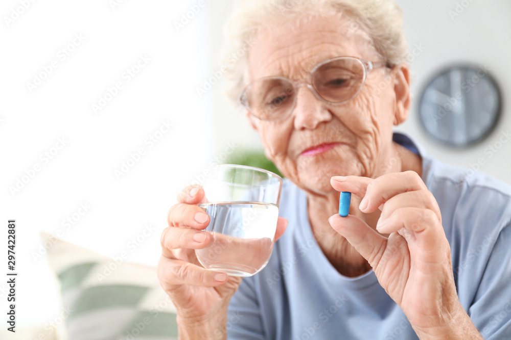 Elderly woman taking pill at home Elderly woman taking pill at home
