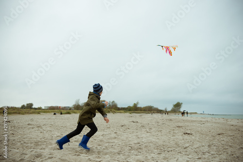 Teen brother and sister playing with kites in sand dunes of Baltic coastline