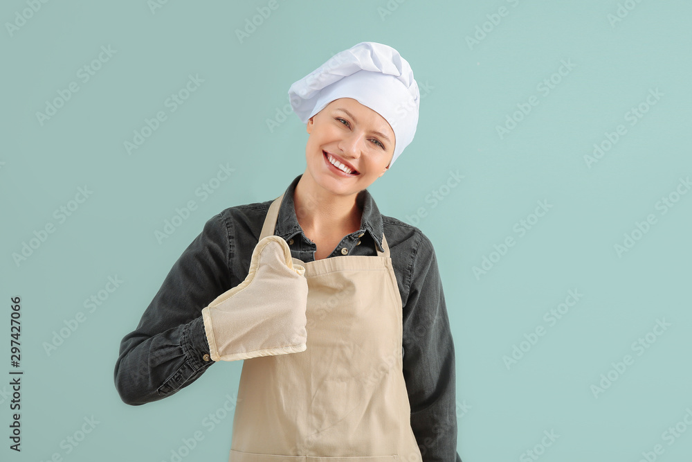 Beautiful female chef showing thumb-up on color background Beautiful female chef showing thumb-up on color background