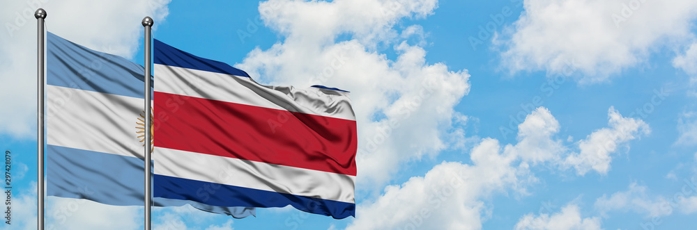 Argentina and Costa Rica flag waving in the wind against white cloudy blue sky together. Diplomacy concept, international relations. Argentina and Costa Rica flag waving in the wind against white cloudy blue sky together. Diplomacy concept, international relations.