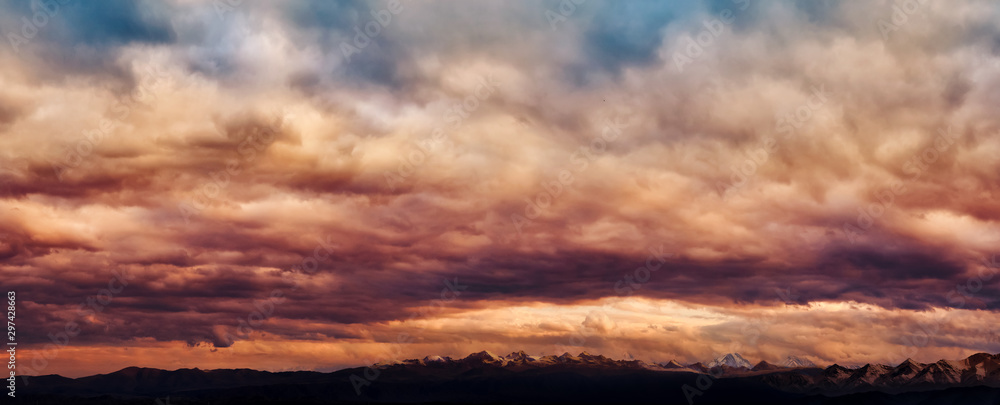 Dramatic light through the clouds against the backdrop of an exciting, vibrant stormy sky at sunset, dawn in the mountains. panorama, natural composition