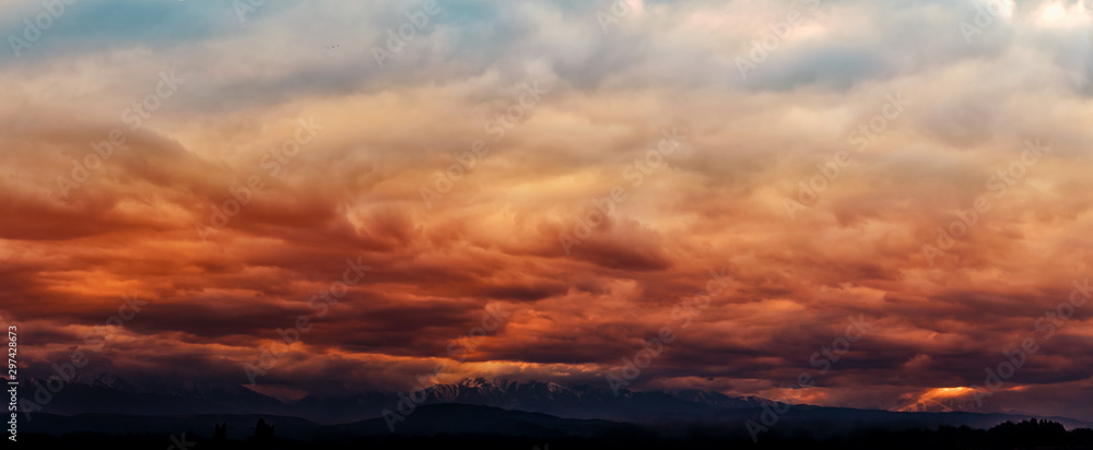 Dramatic light through the clouds against the backdrop of an exciting, vibrant stormy sky at sunset, dawn in the mountains. panorama, natural composition