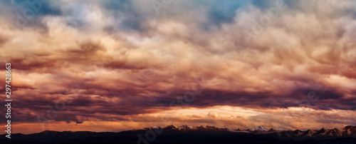 Dramatic light through the clouds against the backdrop of an exciting  vibrant stormy sky at sunset  dawn in the mountains. panorama  natural composition
