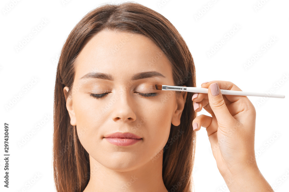 Makeup artist working with beautiful young woman on white background