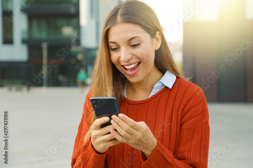 Obraz na plátne Surprised euphoric cheerful woman watching her smart phone in city square