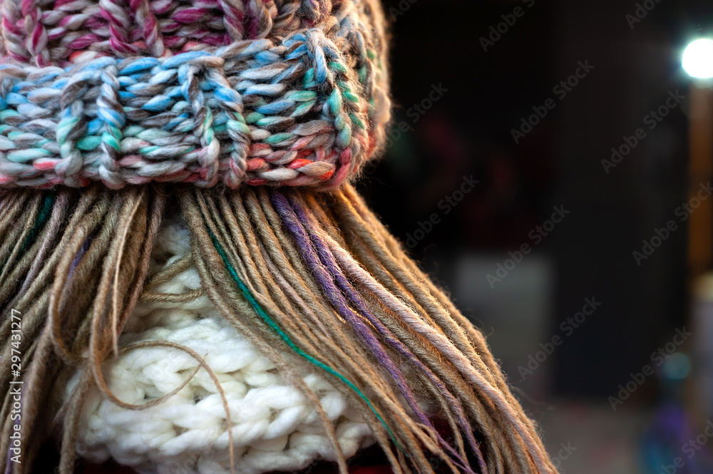 Close-up of a human head with dreadlocks, knitted hat and white knitted scarf, no face