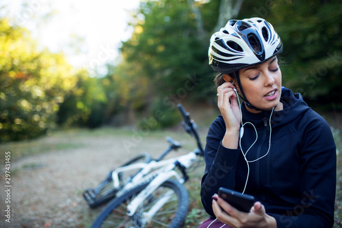 Portrait of female cyclist listening music with earphones