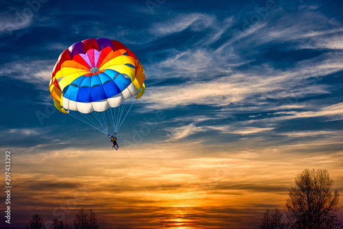 A man is gliding with a parachute on the background of sunset.