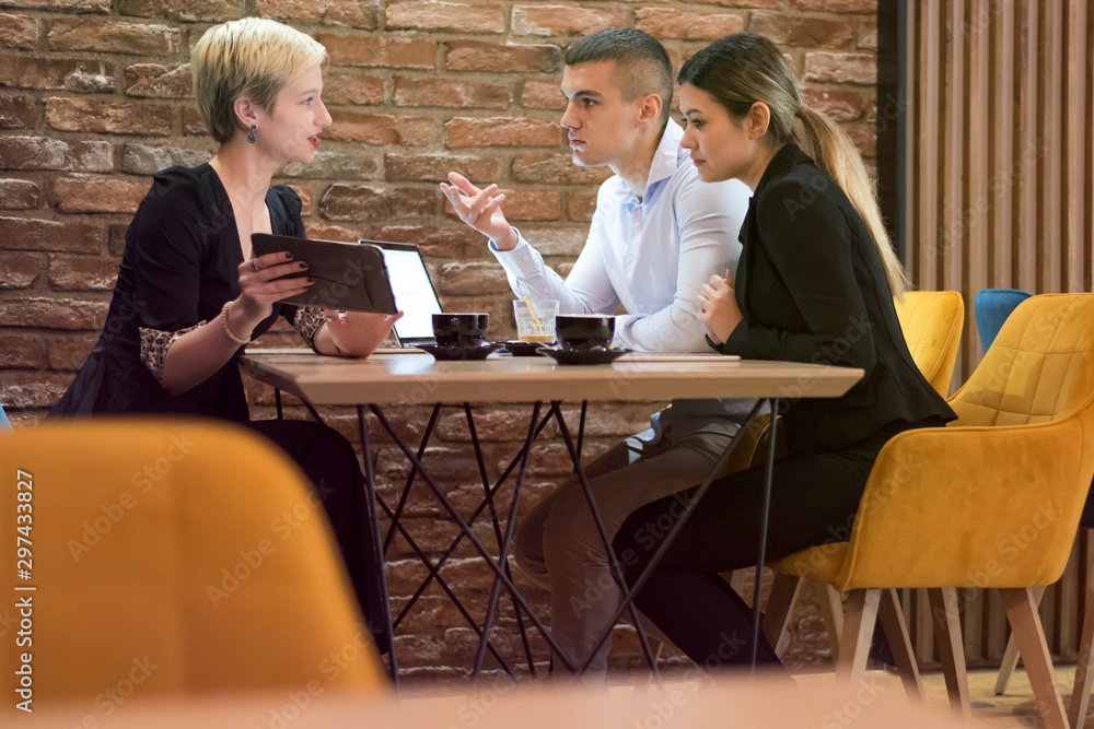 Group of a young business people brainstorming and discussing business plan on meeting at sunny bright office interior.