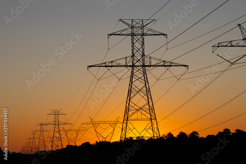 Obraz na plátne The sun rising behind a pair of towering electricity pylons