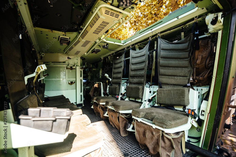 Interior view of empty multi-role armored military vehicle personnel carrier interior with chairs for infantry soldiers inside reconnaissance vehicle