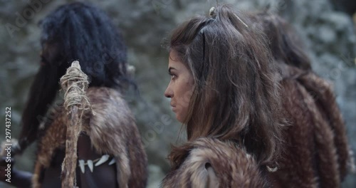 Caveman woman man neanderthals wearing animal skin holding weapon stand beating screaming breasts in prehistoric forest ancient bushman aboriginal evolution hunter stone primitive cave slow motion photo