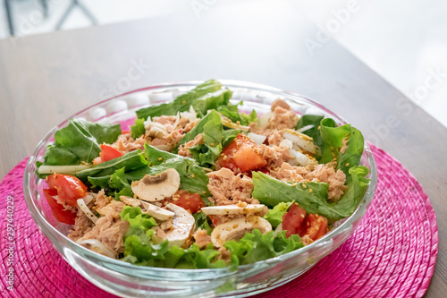 Salad with lettuce, tomato, mushrooms and fish. Pink tablecloth