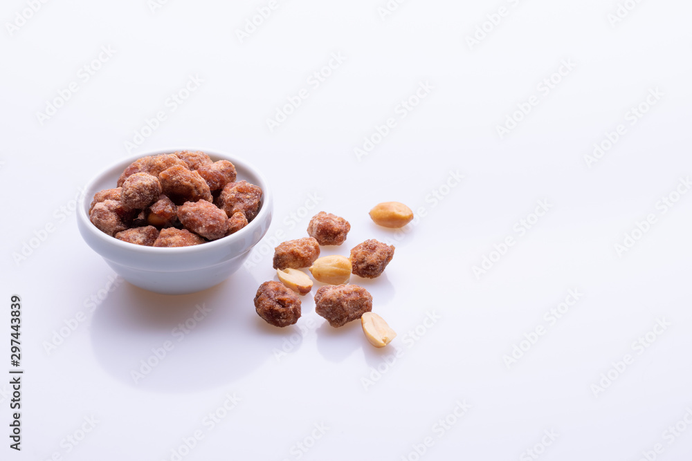 Peanuts praline sweet in a white bowl, on white background, soft light, copy space Peanuts praline sweet in a white bowl, on white background, soft light, copy space