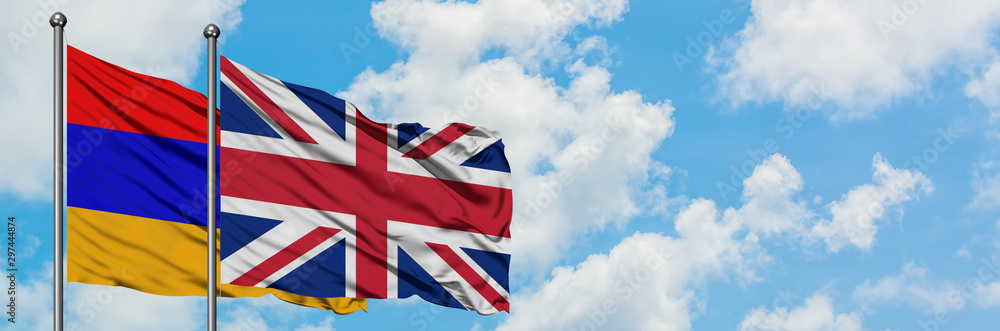 Armenia and United Kingdom flag waving in the wind against white cloudy blue sky together. Diplomacy concept, international relations. Armenia and United Kingdom flag waving in the wind against white cloudy blue sky together. Diplomacy concept, international relations.