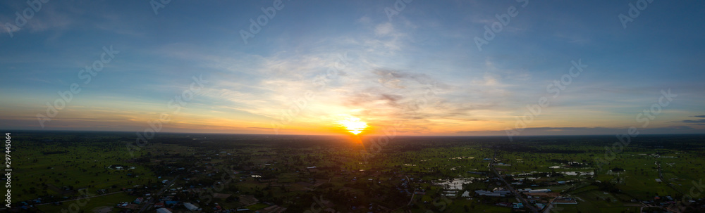Panorama Top view Aerial photo from flying drone over village in Thailand.Cumulus sunset clouds with sun setting down on dark background. Panorama Top view Aerial photo from flying drone over village in Thailand.Cumulus sunset clouds with sun setting down on dark background.