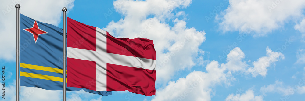 Fototapeta premium Aruba and Denmark flag waving in the wind against white cloudy blue sky together. Diplomacy concept, international relations.