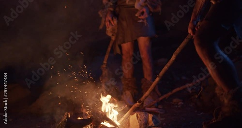 In dark two cavemen stand by the fire at night in a cave stone fun male ancient history stone age primeval evolution nature neanderthal homo sapiens bonfire man tribe campfire wild slow motion
