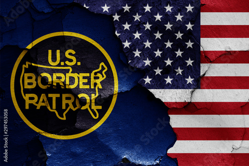 flags of United States Border Patrol and USA painted on cracked wall