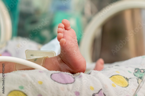 Premature baby´s foot inside an incubator with a cuff for blood pressure measurement. Critically ill. NICU. Neonatology.
