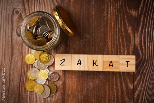 Zakat Islamic Concept. “ZAKAT” wordings wih coins in jar on wooden background