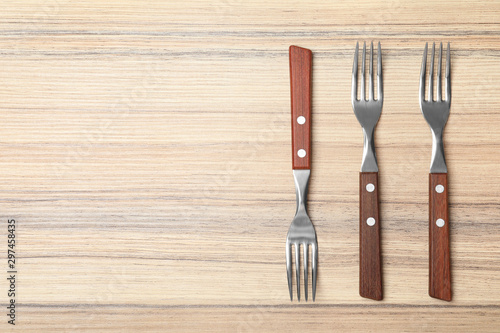 New forks on wooden table, flat lay with space for text