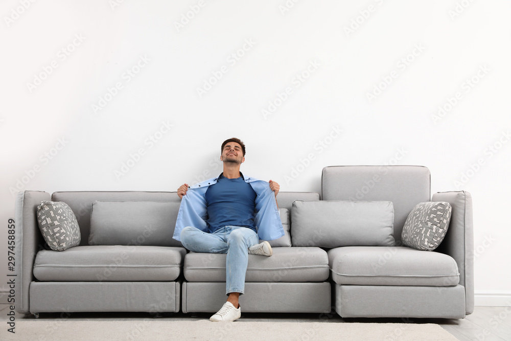 Young man relaxing on sofa against white wall Young man relaxing on sofa against white wall