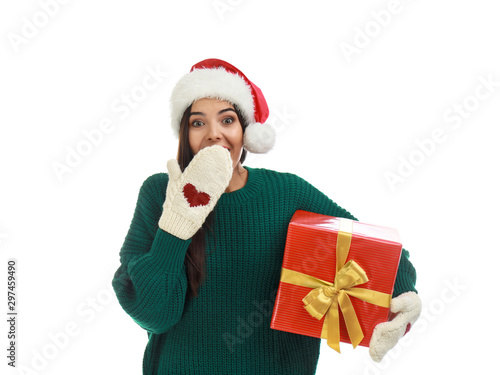 Happy young woman in Santa hat with Christmas gift on white background