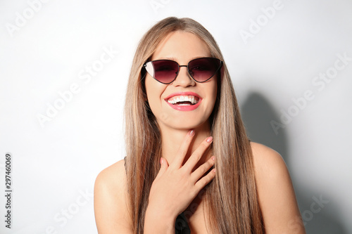 Young woman wearing stylish sunglasses on light background © New Africa