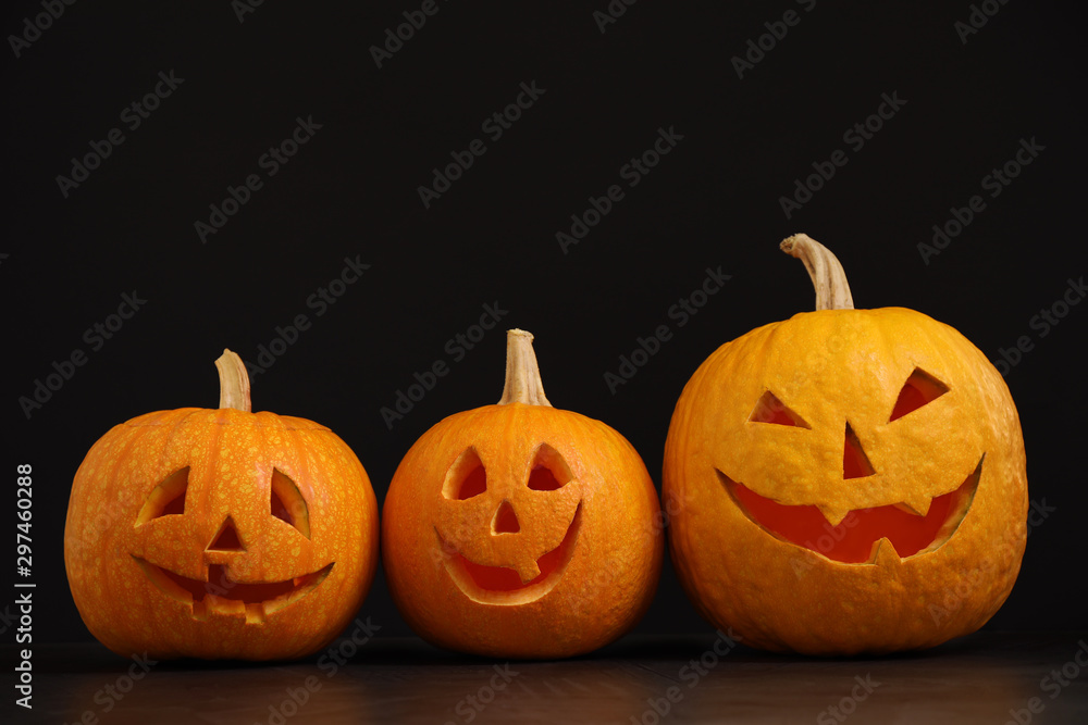 Spooky Jack pumpkin head lanterns on grey table against black background, space for text. Halloween decoration Spooky Jack pumpkin head lanterns on grey table against black background, space for text. Halloween decoration