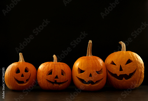 Spooky Jack pumpkin head lanterns on grey table against black background, space for text. Halloween decoration