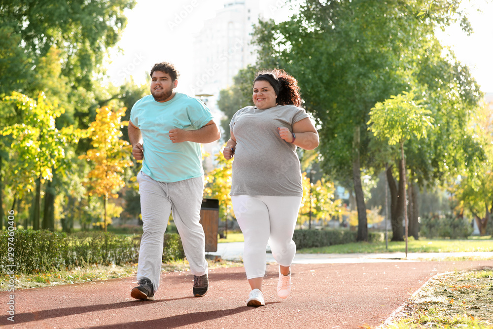 Overweight couple running together in park on sunny day Overweight couple running together in park on sunny day