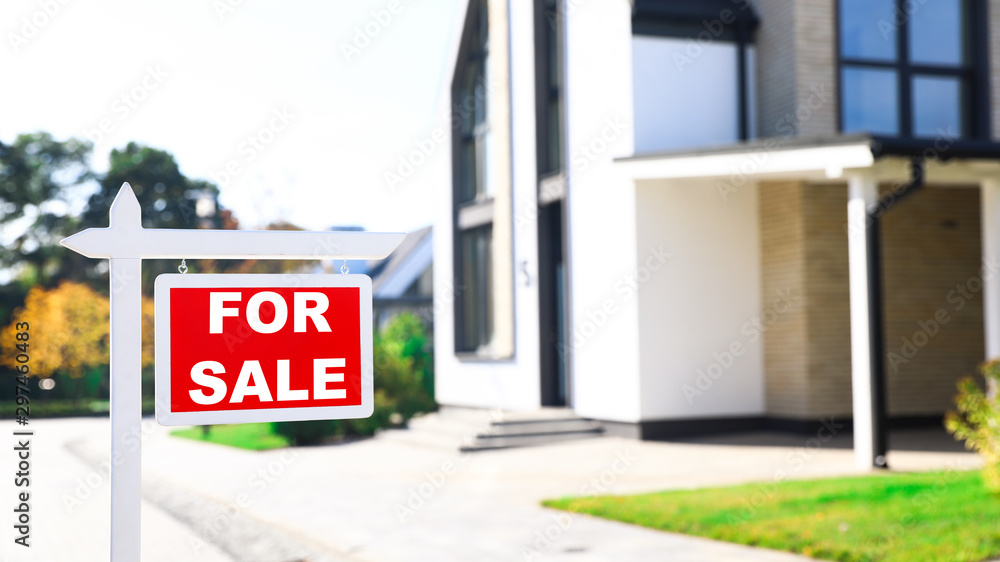Red real estate sign near house outdoors on sunny day Red real estate sign near house outdoors on sunny day