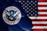 flags of Department of Homeland Security and USA painted on cracked wall