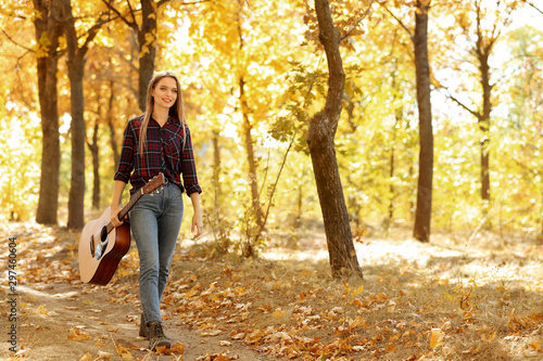 Teen girl with acoustic guitar in autumn park