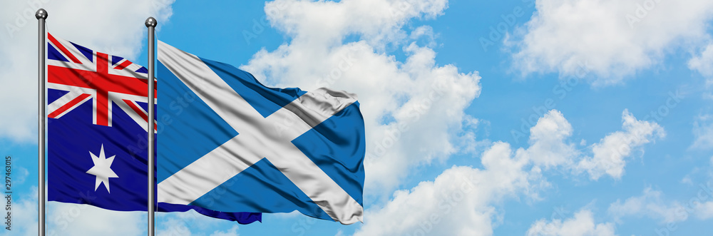 Australia and Scotland flag waving in the wind against white cloudy blue sky together. Diplomacy concept, international relations. Australia and Scotland flag waving in the wind against white cloudy blue sky together. Diplomacy concept, international relations.
