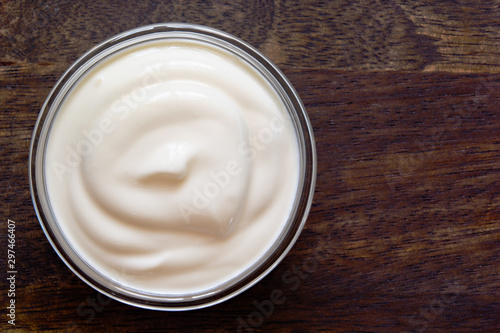 Yogurt, sour cream bowl on wood background. Healthy dairy food, white sauce portion