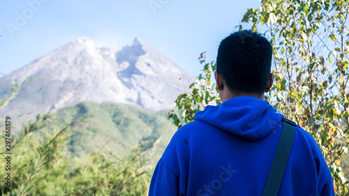 a man with blue jacket  stand in front of beautiful Merapi Mountain in Yogyakarta  Indonesia