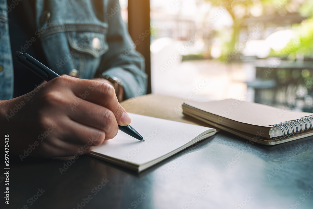 Closeup image of a woman writing on a blank notebook on wooden table Closeup image of a woman writing on a blank notebook on wooden table