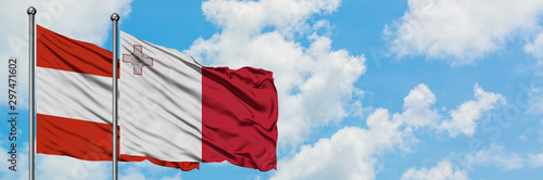 Austria and Malta flag waving in the wind against white cloudy blue sky together. Diplomacy concept, international relations.