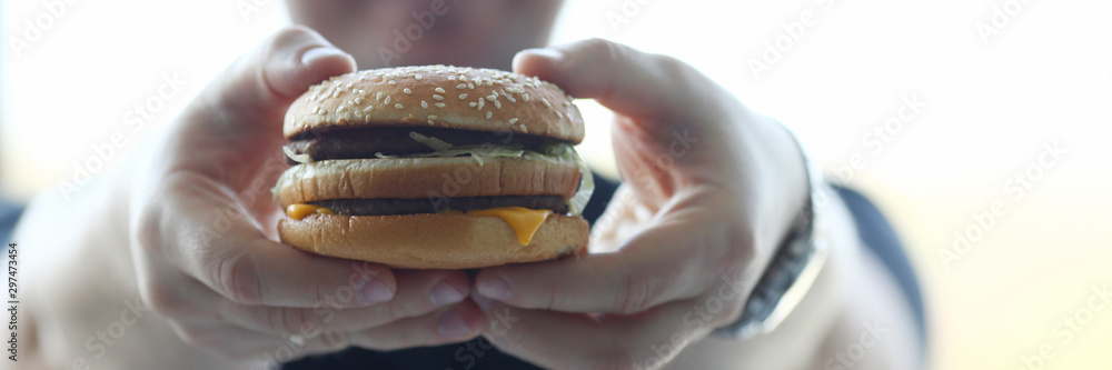 Satisfied young man holding a hamburger Satisfied young man holding a hamburger