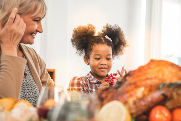 Thanksgiving Celebration Tradition Family Dinner Concept.family having holiday dinner and cutting turkey.Young black adult woman and her daughter happy.