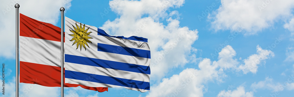 Fototapeta premium Austria and Uruguay flag waving in the wind against white cloudy blue sky together. Diplomacy concept, international relations.