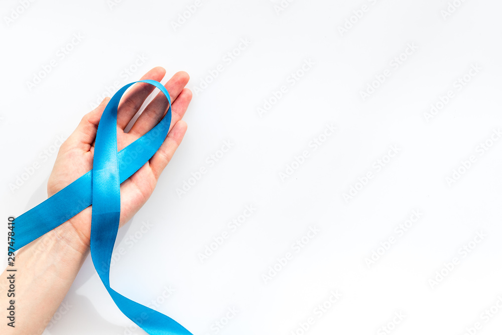 Blue ribbon in hands as symbol disease control on white background top view copy space Blue ribbon in hands as symbol disease control on white background top view copy space