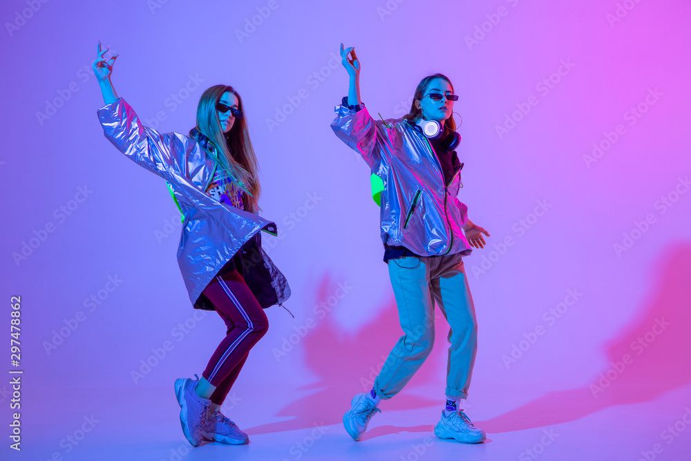 Fototapeta premium Young stylish girls dancing in the Studio on a colored neon background. Music dj poster design.