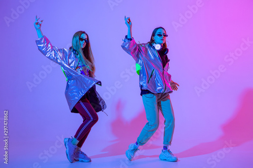 Young stylish girls dancing in the Studio on a colored neon background. Music dj poster design.