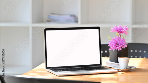 Comfortable workspace with laptop, coffee and flower.