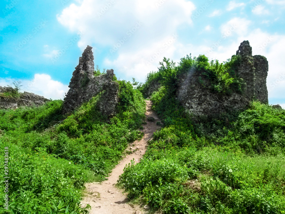Ruins of the Upper Castle in Khust (Transcarpathia, Ukraine). Destroyed stone tower among spring bright green nature against the blue sky